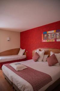 een hotelkamer met 2 bedden en een rode muur bij Kyriad Nîmes Ouest A9 in Nîmes