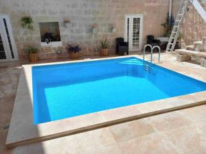 a swimming pool with blue water in a yard at The Gem Farmhouse by Homely in Santa Venera