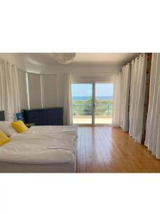 a bedroom with a bed and a large window at Villa Caretta - direkt an einem einsamen Strand im Süden des Peloponnes in Áyioi Taxiárkhai