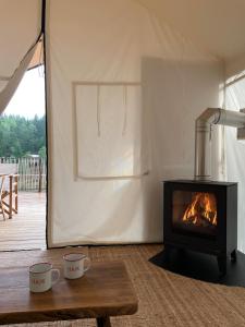 a fireplace in a tent with two cups on a table at HAJK Österlen in Ludaröd