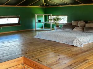 a green bedroom with a bed and a wooden floor at Pirts māja in Kuldīga