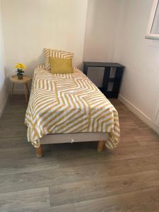 a bed with a yellow and white comforter in a room at Charmante chambre dans maison tout confort proche Orly et Paris in Villeneuve-le-Roi