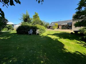 a yard with two chairs in the grass at Gîte La Maison d'Amélie in La Chapelle-Saint-Aubert
