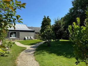 a garden with a house and a gravel path at Gîte La Maison d'Amélie in La Chapelle-Saint-Aubert