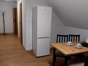 a white refrigerator in a room with a wooden table at Domki, pokoje, apartamenty Agata Kunowska in Ostrzyce