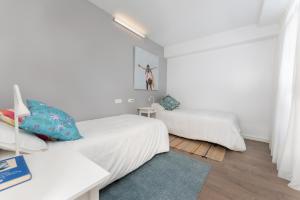 テルデにあるLa Casa De La Playaの白いベッドルーム(ベッド2台、青いラグ付)
