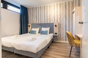 a bedroom with a large bed and a chair at Hello Zeeland - Appartement Duno Lodge I in Oostkapelle
