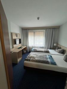 a hotel room with two beds and a desk at Hotel Regina in Sankt Augustin