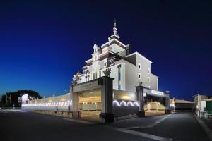 犬山市Hotel Embassy Inuyama的一座白色的大建筑,晚上有钟楼
