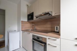 a kitchen with white cabinets and a sink and a refrigerator at Appartement Arcico - Welkeys in Boulogne-Billancourt +9 photos