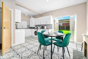 a kitchen with a table and green chairs at Cozy 3-bed house ideal for families and contractors with Netflix 7 miles for Birmingham City Centre in Oldbury