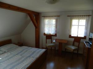 a bedroom with a bed and a desk and two windows at Privát Fedoriška in Špindlerův Mlýn