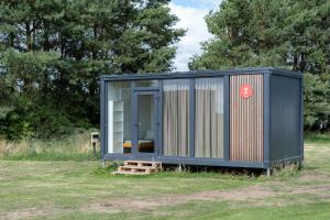 a black tiny house sitting in a field at BoardHouse Spot in Svencelė