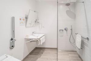 a white bathroom with a shower and a sink at Hotel Italia in Trieste