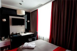 a hotel room with a bed and a desk and a television at Mildom Premium Hotel in Almaty