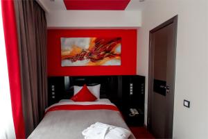 a bedroom with a bed with a red wall at Mildom Premium Hotel in Almaty