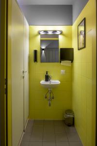 a yellow bathroom with a sink and a mirror at UrbanKey Studios - Vienna Neubau in Vienna +28 photos