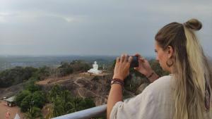 a woman taking a picture of a monument at Lake Wave Hotel in Anuradhapura