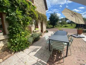 un tavolo e sedie con ombrellone accanto a un edificio di Gîte écologique de charme avec grand jardin, proche des Alpes Mancelles, idéal famille et amis - FR-1-410-132 a Moulins-le-Carbonnel