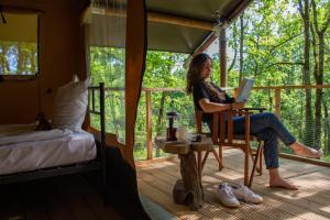 a woman sitting on the porch of a tent reading a book at Le Camp in Varen