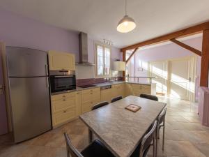 a kitchen with a table and a stainless steel refrigerator at Charmante fermette rénovée avec cour privée, proche de Paris et facile d'accès par autoroutes - FR-1-590-17 in Aschères-le-Marché