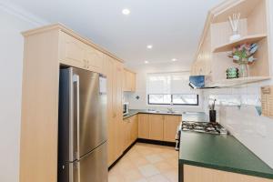 Una cocina con refrigerador y gabinetes de acero inoxidable. en 4-1 Penders Court, en Jindabyne