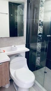 a bathroom with a toilet and a glass shower at Aparta-hotel Eskala UPTC in Tunja +12 photos