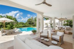 a living room with white furniture and a swimming pool at One Westland Heights villa in Saint James