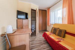 a hotel room with a bed and a desk and a television at Pokoje Gościnne Lipowa in Sztutowo