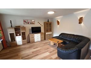 a living room with a leather couch and a table at Ferienwohnung Lidwina in Steinwiesen