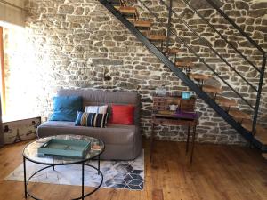 a living room with a couch and a stone wall at TyAngeLLouis in Brandivy +12 photos