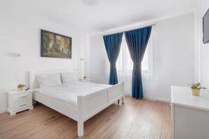 Una cama blanca con cortinas azules en un dormitorio en Thermalis Groove, en Băile Felix