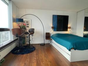 a bedroom with a bed with a blue blanket and a desk at Panoramique vue NEW design proche Tour Eiffel in Paris