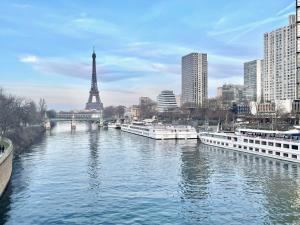 a river with boats in a city with the eiffel tower at Panoramique vue NEW design proche Tour Eiffel in Paris