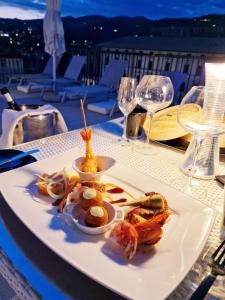 a white plate with food on a table with wine glasses at LHP Hotel Montecatini Palace & SPA in Montecatini Terme
