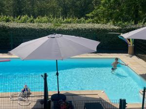 a man in a swimming pool with an umbrella at Les Hauts de Courrech in Grézels