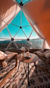 un tavolo e delle sedie in una stanza con una grande finestra di Handeland Lodge I Arctic Dome a Sauda Altre 31 foto