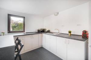 Una cocina con gabinetes blancos y un fregadero y una ventana. en Thermalis Groove, en Băile Felix 27 fotos más
