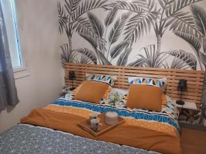 a bed with two pillows and a wall with plants at Petit studio independant mitoyen à la maison in Jaunay-Clan