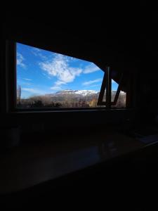 - une fenêtre dans une chambre sombre avec vue sur la montagne dans l'établissement Tranquera's house, à San Martín de los Andes