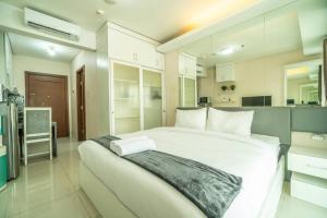 a bedroom with a large white bed and a kitchen at Peaceful studio in central Jakarta, SCBD, Thamrin in Jakarta