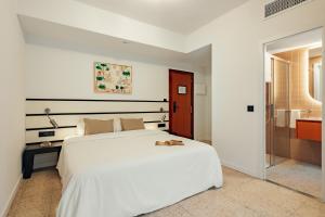 a bedroom with a large white bed and a bathroom at Hotel Robson - Smart Hotel in Lloret de Mar