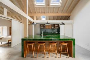 MogrovejoにあるApartamentos Luarnaのキッチン(緑のカウンタートップ、スツール付)