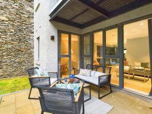 a patio with three chairs and a table on a patio at Wild Roses Serviced Apartments - Lake District in Backbarrow