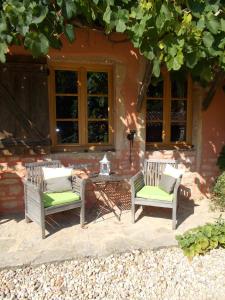2 chaises et une table en face d'une maison dans l'établissement La Cassinette, à Romenay