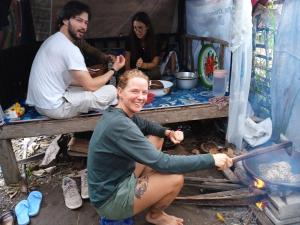 a woman sitting on a table with a stove at Citra Homestay in Tetebatu