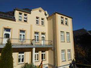 ein gelbes Gebäude mit Balkon darüber in der Unterkunft Pension Fürstenhof in Bad Elster