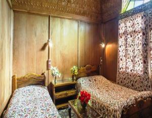 a bedroom with two beds and a table with flowers at New Lucky Star Group of Houseboats in Srinagar