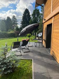eine Terrasse mit Sonnenschirm, Stühlen und einem Tisch in der Unterkunft Notre Chalet - Boutique Appartements 4 étoiles & Sauna in Les Fourgs