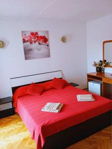 a bedroom with a red bed with two towels on it at Rooms Helena in Krk